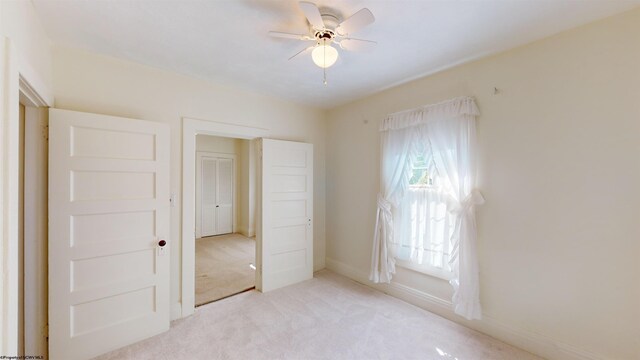 unfurnished bedroom with ceiling fan, light colored carpet, and a closet