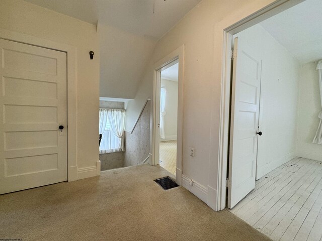 corridor with light carpet and lofted ceiling