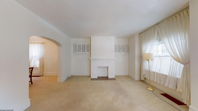 unfurnished living room with light carpet and a fireplace