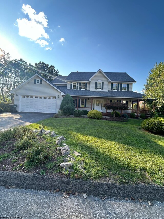 view of front of property with a front yard, a garage, and a porch