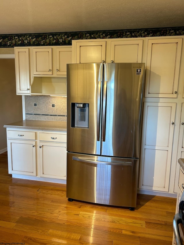 kitchen with backsplash, stainless steel refrigerator with ice dispenser, and light hardwood / wood-style floors