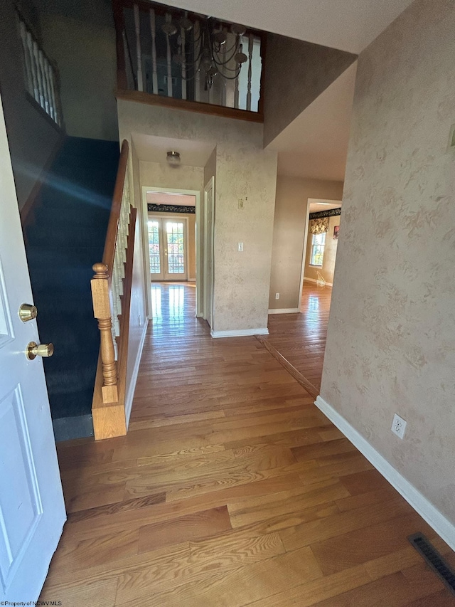 hall with plenty of natural light, wood-type flooring, and a high ceiling