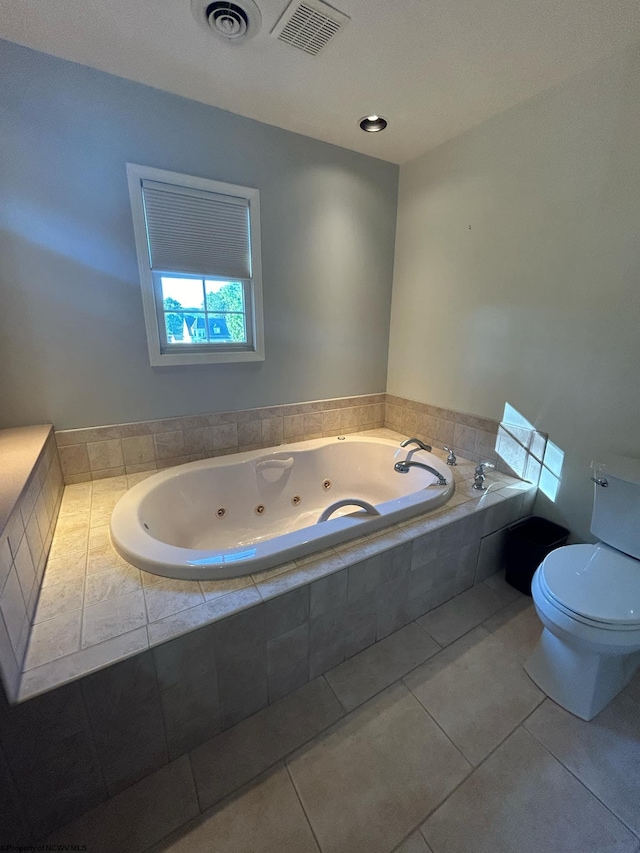 bathroom featuring toilet, tiled bath, and tile patterned flooring