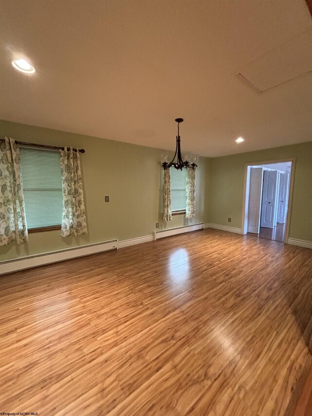 unfurnished living room featuring light hardwood / wood-style flooring, an inviting chandelier, and a baseboard radiator