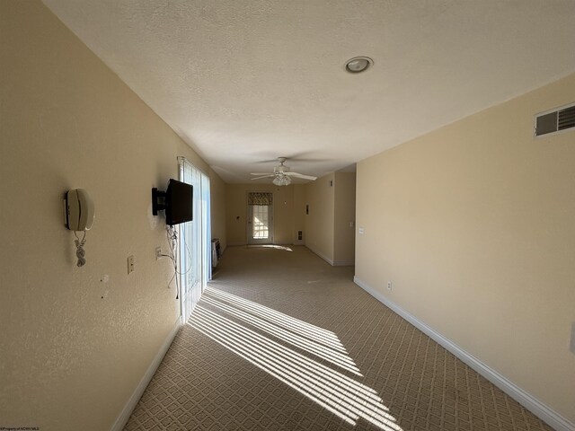 hallway with a textured ceiling and carpet floors