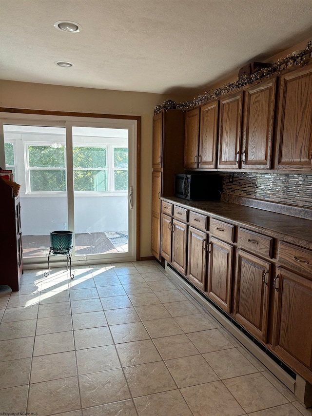 kitchen with a textured ceiling, light tile patterned floors, and decorative backsplash