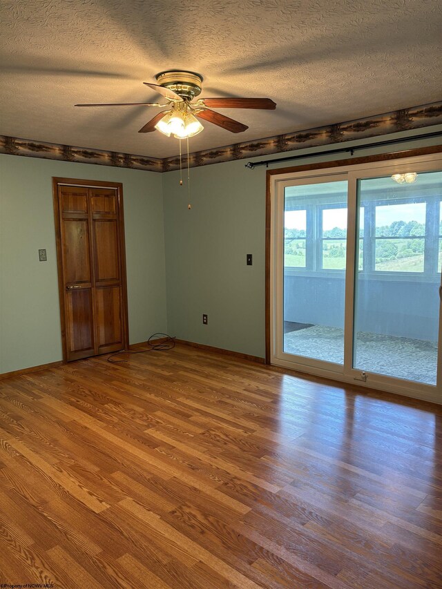 unfurnished room with ceiling fan, a textured ceiling, wood-type flooring, and a healthy amount of sunlight