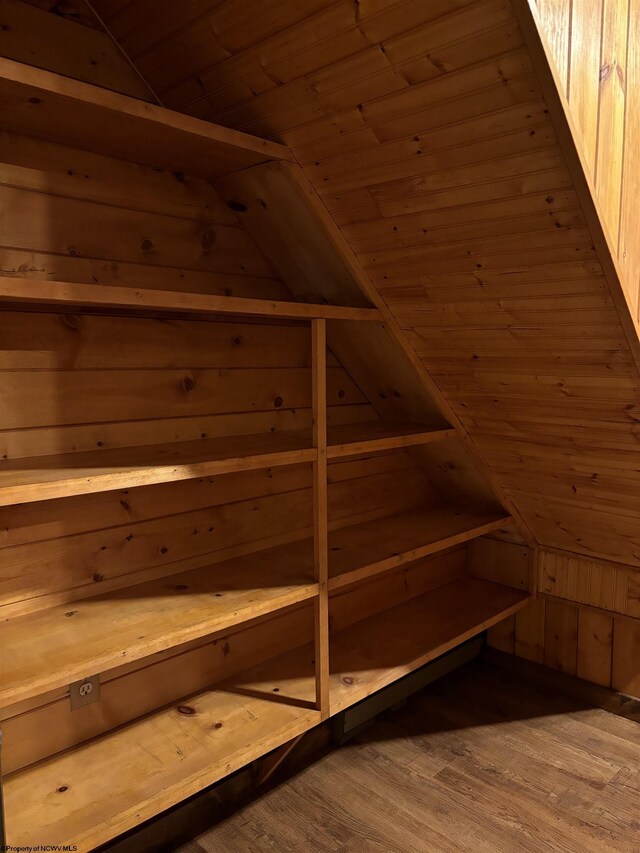 bonus room featuring lofted ceiling, light hardwood / wood-style flooring, and wooden walls