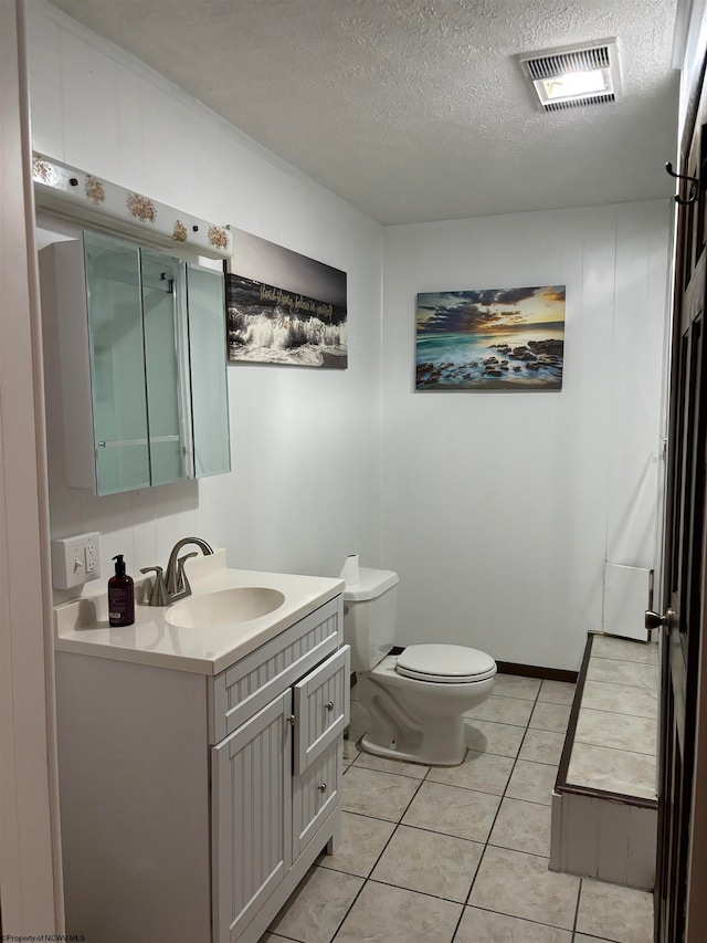 bathroom featuring a textured ceiling, vanity, tile patterned flooring, and toilet