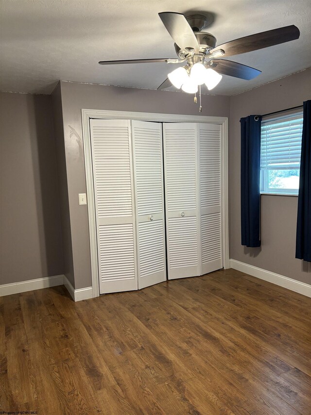 unfurnished bedroom featuring ceiling fan, wood-type flooring, and a closet