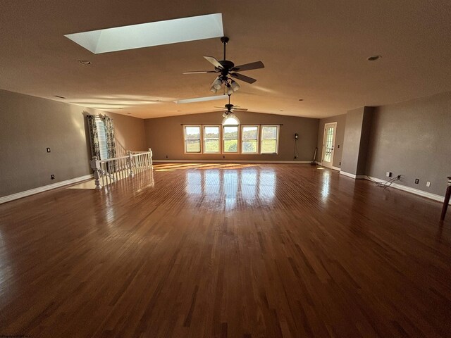 unfurnished living room with ceiling fan, dark wood-type flooring, and lofted ceiling with skylight