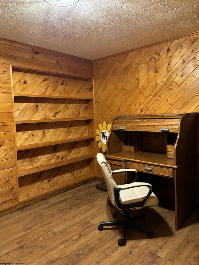 office area featuring a textured ceiling, wooden walls, and wood-type flooring