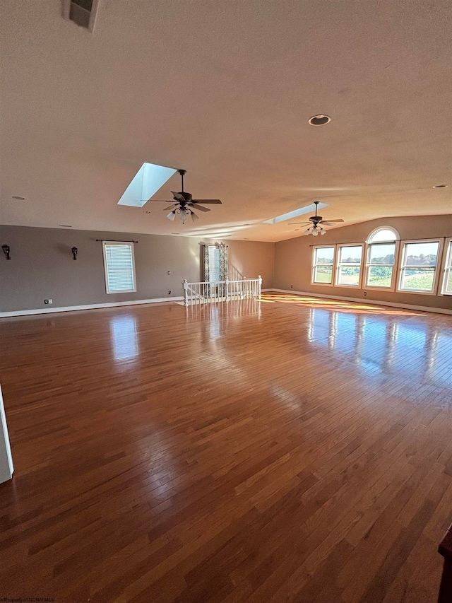 unfurnished room with ceiling fan, a skylight, and hardwood / wood-style flooring