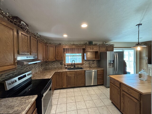 kitchen featuring stainless steel appliances, sink, light tile patterned floors, decorative backsplash, and wall chimney exhaust hood