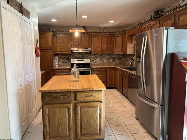 kitchen with light tile patterned flooring, stainless steel appliances, decorative backsplash, a kitchen island, and butcher block countertops