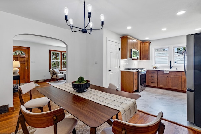 dining room featuring light wood-type flooring, sink, and a chandelier