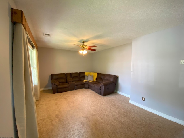 carpeted living room featuring ceiling fan and a textured ceiling