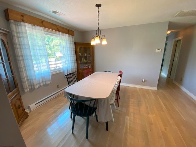 dining area with light wood-type flooring, a baseboard radiator, and an inviting chandelier