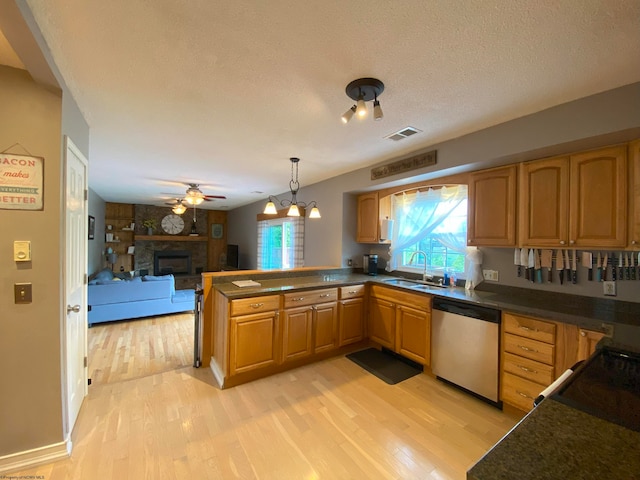 kitchen with light hardwood / wood-style flooring, a stone fireplace, a textured ceiling, and dishwasher