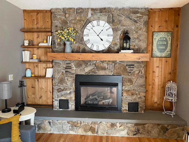 details featuring a textured ceiling, a stone fireplace, and hardwood / wood-style floors