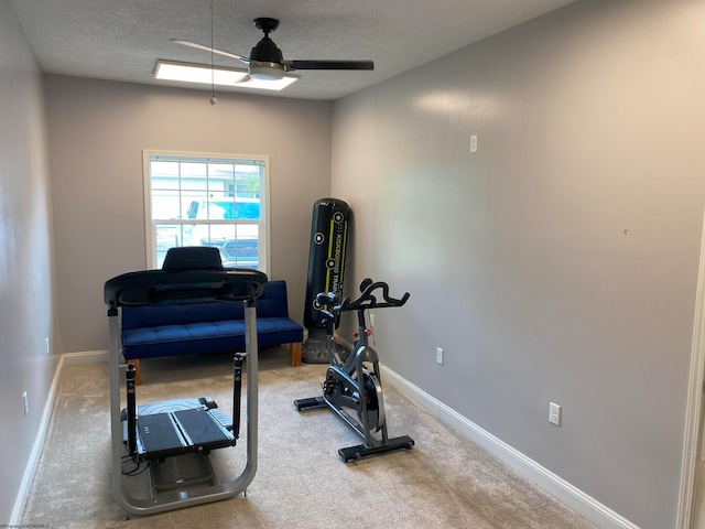 exercise area featuring ceiling fan, a textured ceiling, and carpet