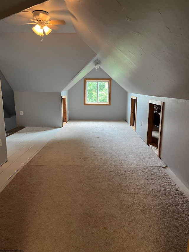 additional living space with ceiling fan, lofted ceiling, and light carpet