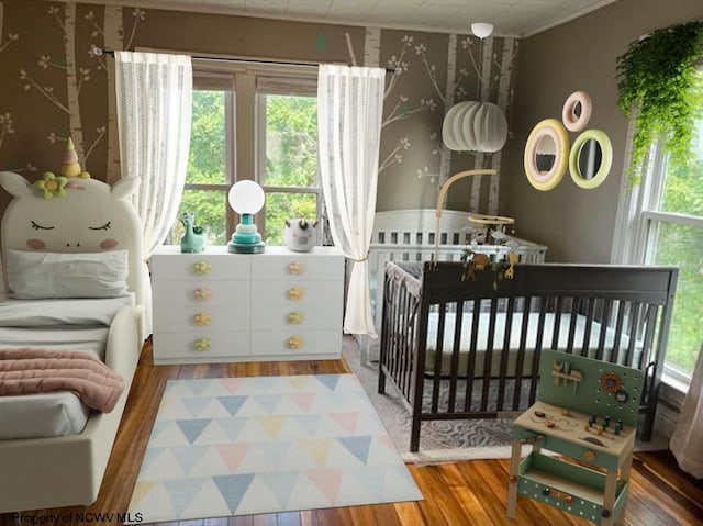 bedroom with hardwood / wood-style flooring and a nursery area