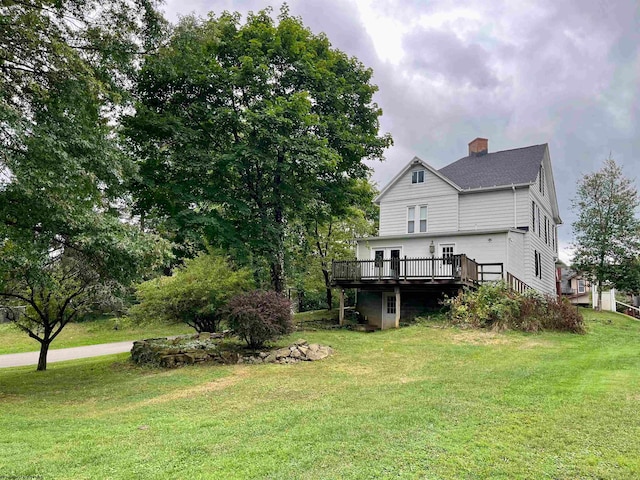 rear view of house featuring a wooden deck and a yard