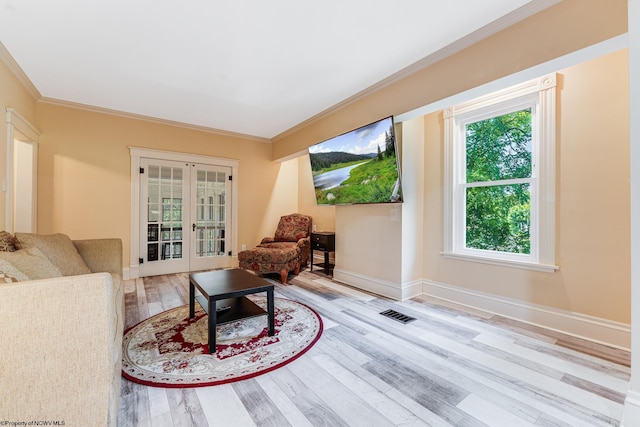 living area featuring crown molding, plenty of natural light, light hardwood / wood-style flooring, and french doors