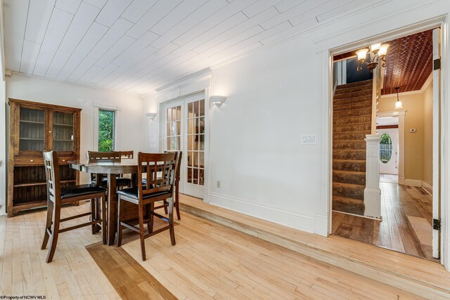 dining space with wooden ceiling, ornamental molding, an inviting chandelier, and light wood-type flooring