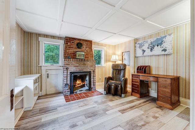 interior space with a brick fireplace, light hardwood / wood-style floors, coffered ceiling, wooden walls, and brick wall