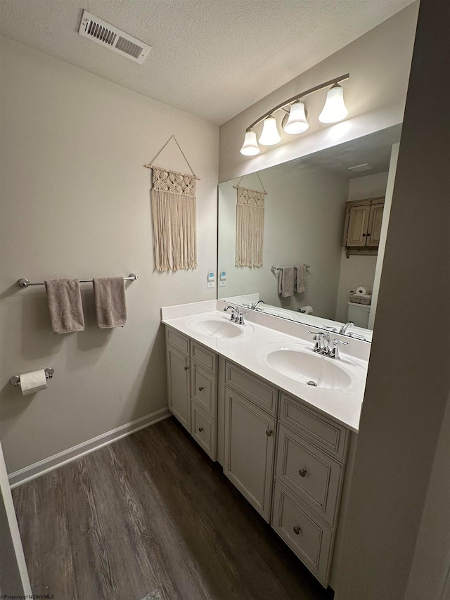 bathroom featuring vanity, wood-type flooring, a textured ceiling, and toilet