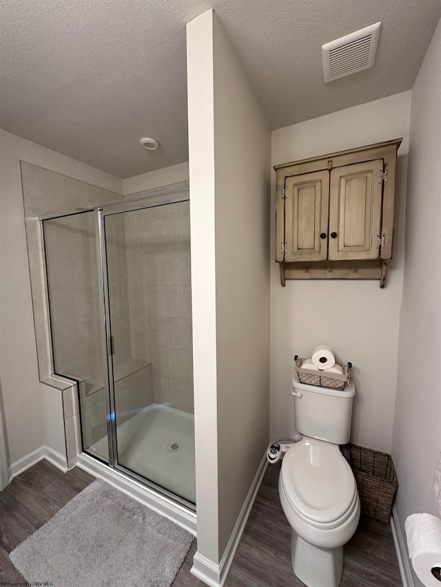 bathroom featuring a textured ceiling, toilet, wood-type flooring, and walk in shower