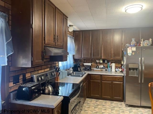 kitchen featuring dark brown cabinets, stainless steel appliances, tasteful backsplash, and sink