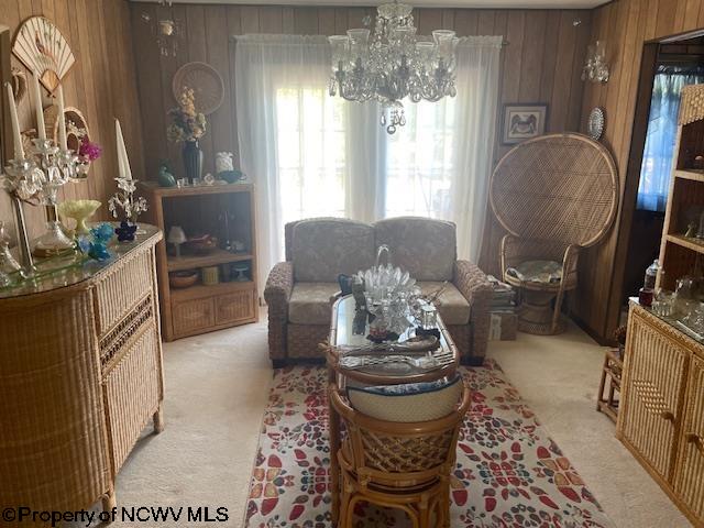 living room with a notable chandelier, wood walls, and light carpet