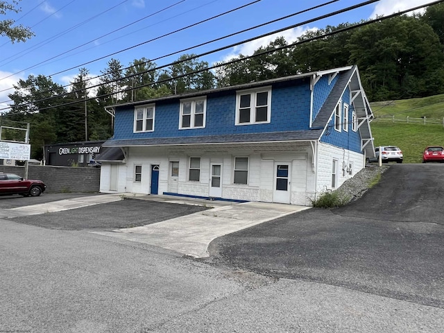 view of property with a front yard, fence, and roof with shingles