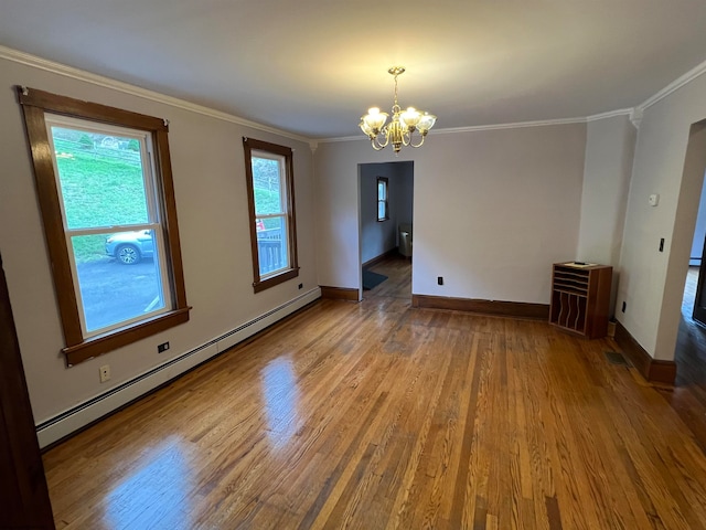 spare room with crown molding, wood-type flooring, a notable chandelier, and baseboard heating