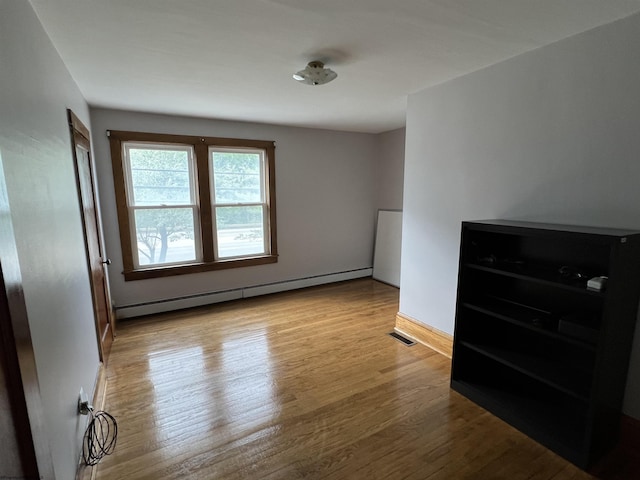 bedroom featuring baseboards, baseboard heating, visible vents, and wood finished floors