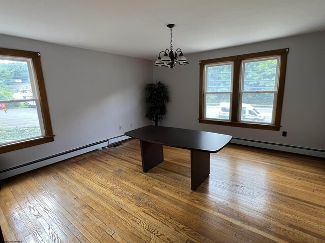 interior space with a wealth of natural light, a chandelier, a baseboard heating unit, and wood-type flooring