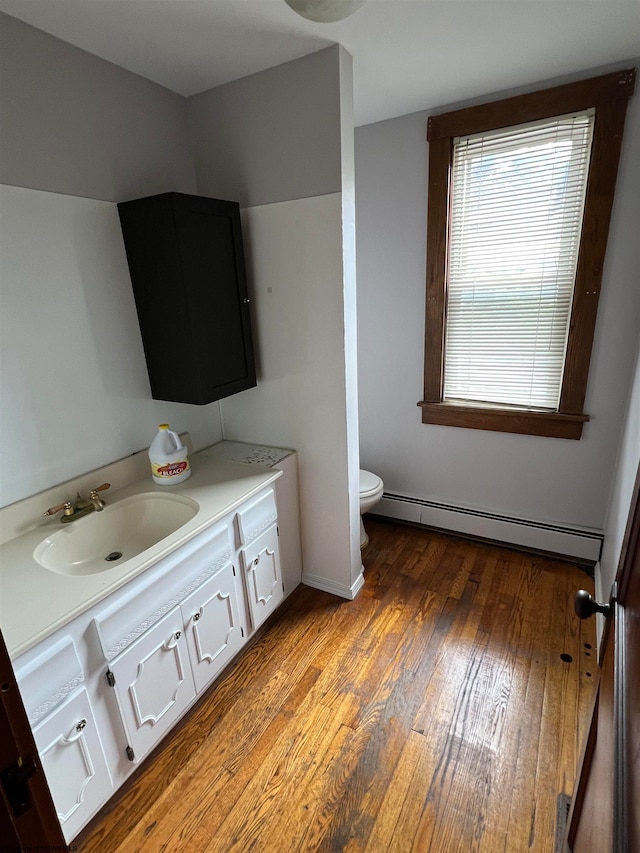 bathroom featuring toilet, vanity, hardwood / wood-style floors, and a baseboard radiator