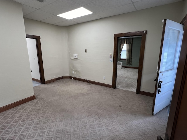 carpeted empty room with a drop ceiling and baseboards