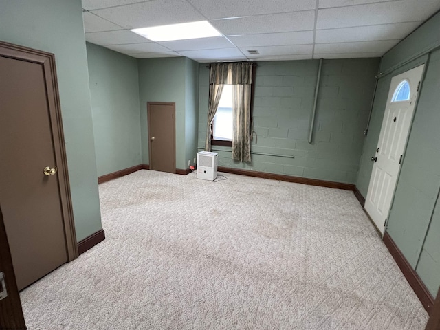 carpeted spare room featuring baseboards, concrete block wall, and a paneled ceiling