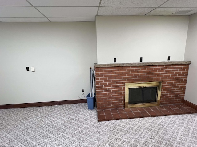 room details with a tiled fireplace, carpet floors, baseboards, and a drop ceiling