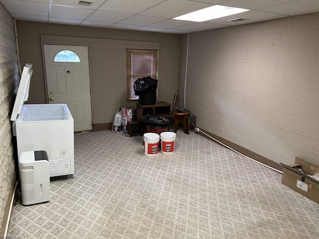 basement with concrete block wall, visible vents, and a paneled ceiling