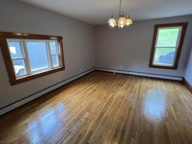 unfurnished room featuring a notable chandelier, baseboard heating, baseboards, and wood finished floors