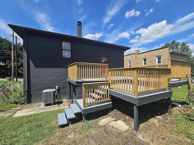 rear view of house featuring a chimney, central AC unit, a deck, and brick siding