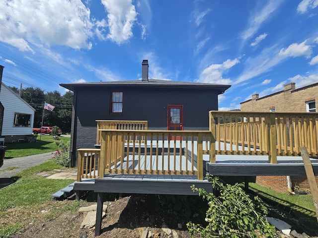 rear view of house featuring a chimney and a wooden deck