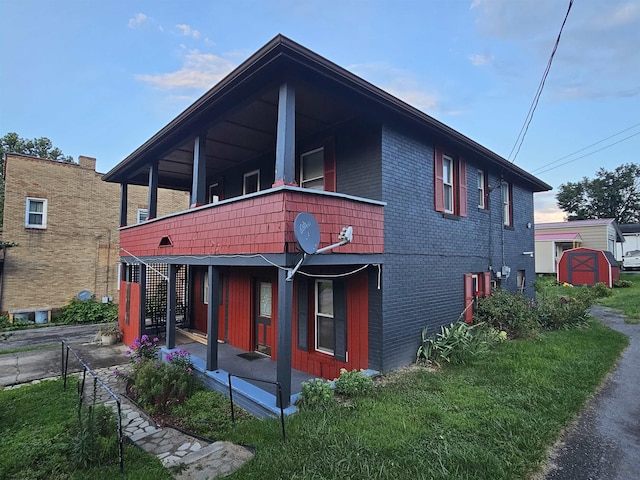 view of front of house featuring a porch, brick siding, and a front lawn