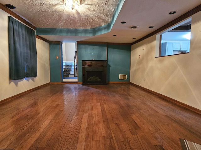 unfurnished living room with visible vents, a fireplace, baseboards, and wood finished floors