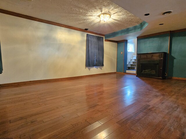 unfurnished living room featuring a textured ceiling, hardwood / wood-style floors, and ornamental molding